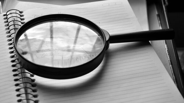 A magnifying glass over a notebook, symbolizing a detailed SEO audit checklist