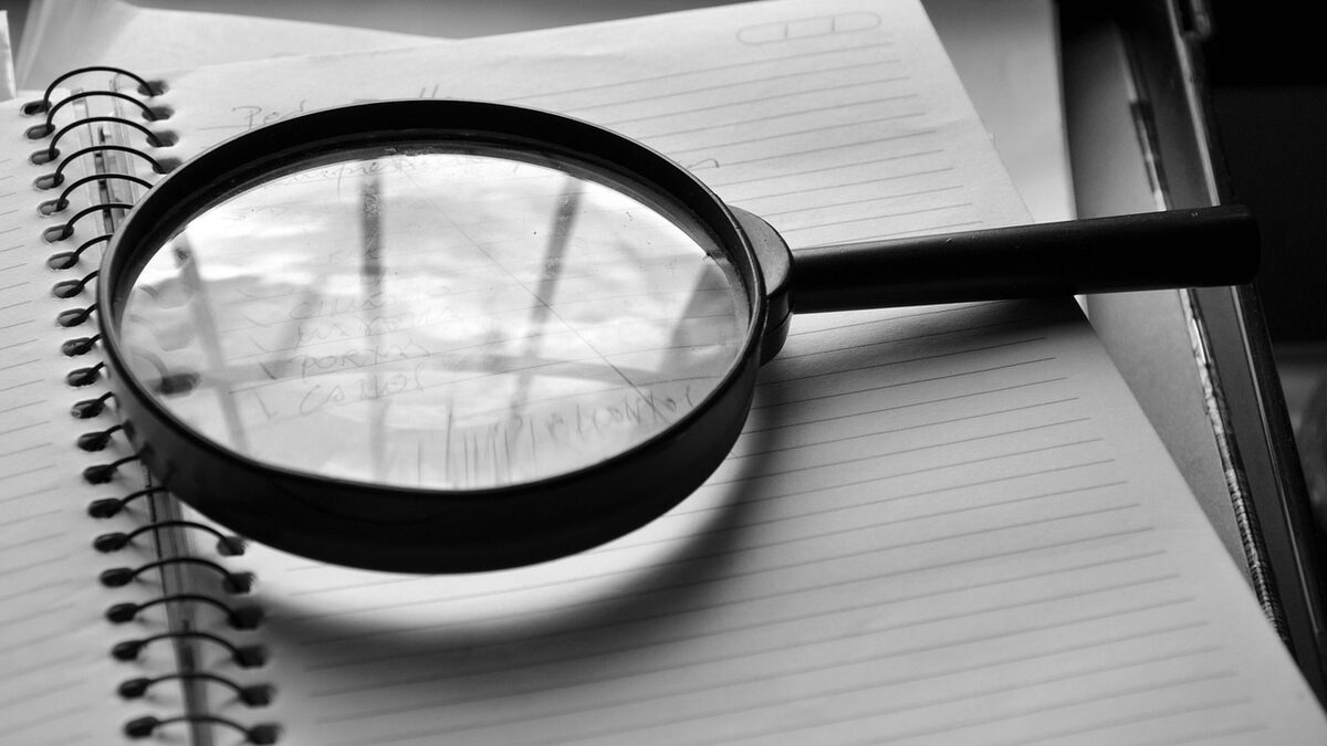 A magnifying glass over a notebook, symbolizing a detailed SEO audit checklist